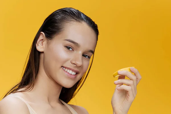 Beautiful woman eating lemon in hands smile vitamins diet yellow background — Stock Photo, Image