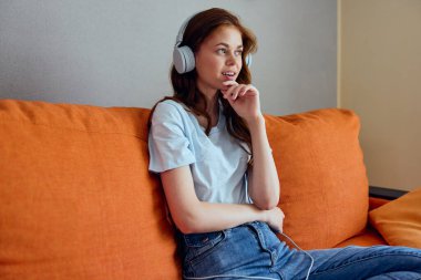 Evdeki güzel kadın kulaklığı kanepe eğlence dairelerinde.