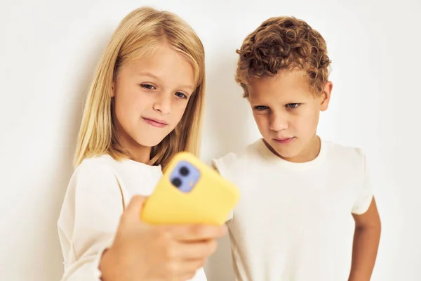 Zwei Vorschulkinder schauen aufs Handy und posieren für ihre Kindheit — Stockfoto