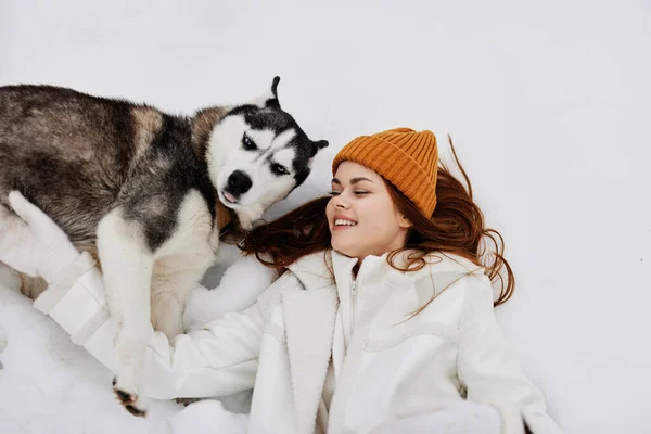 Glad ung kvinna vinter kläder rastar hunden i snön frisk luft — Stockfoto