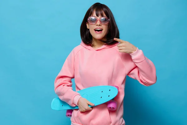 핑크 스웨터를 입고 스케이트 보드 엔터 테인 먼 트 청색 배경을 가진 아름다운 여성 — 스톡 사진