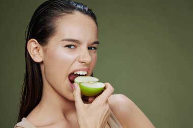 Yeşil elma gülüşlü, izole bir arka planı olan bir portre kadını.