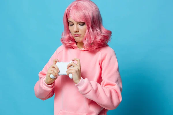 Hermosa mujer con un joystick en las manos del juego posando fondo azul — Foto de Stock