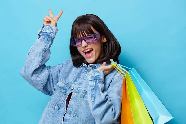 Mulher em jaquetas jeans com sacos de compras coloridos isolado fundo — Fotografia de Stock