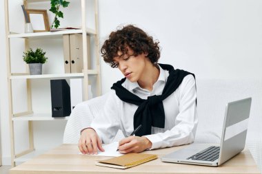 Dizüstü bilgisayarın önünde beyaz bir kanepede oturan bir adam.