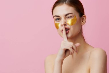 Güzel kadın, gençleştirme cilt bakımını duştan sonra pembe arka planda tutuyor.