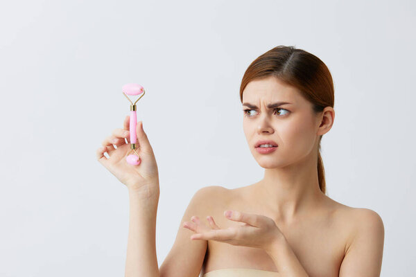 beautiful woman pink quartz roller scraper skin care massage bare shoulders close-up Lifestyle