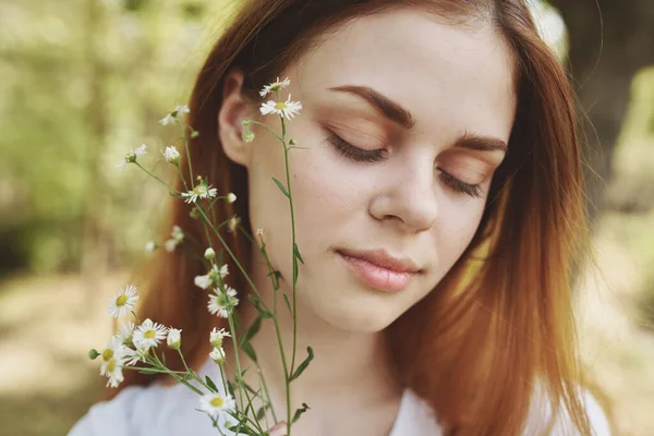 Ritratto di una bella donna con fiori di campo e con gli occhi chiusi sulla natura in un prato — Foto Stock