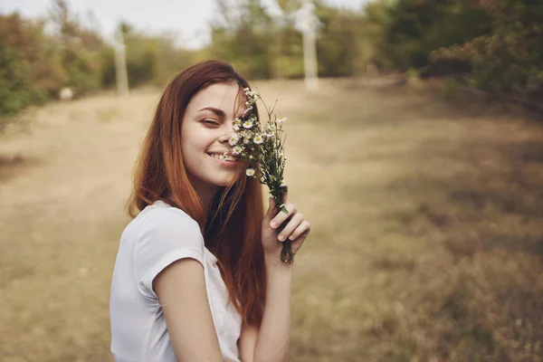 Mulher romântica com buquê de flores silvestres perto de árvores no campo — Fotografia de Stock