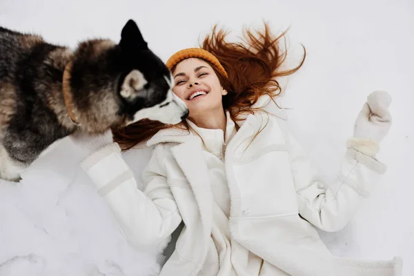 Retrato de uma mulher na neve brincando com um cão diversão amizade férias de inverno — Fotografia de Stock