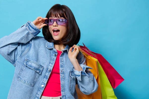 Jovem mulher em óculos de sol compras emoções posando alegria fundo azul — Fotografia de Stock