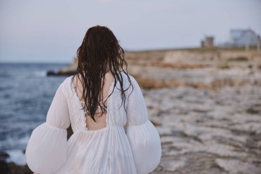 Okyanus taşlarının yanındaki kadın geriye doğru yürüyor. Yüksek kalite fotoğraf