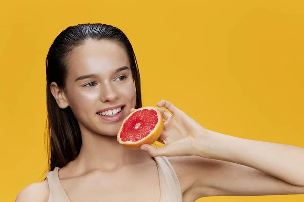 Brunette with grapefruit near face clean skin care health yellow background — Stock Photo, Image