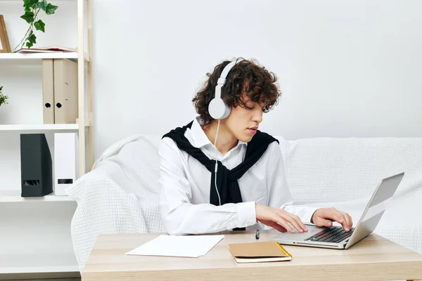 Bouclé gars ordinateur portable dans les écouteurs sur canapé blanc technologie Lifestyle — Photo