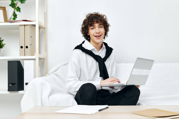 Curly guy on a white sofa in front of a laptop learning living room Royalty Free Stock Photos