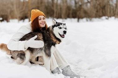 Karda oynayan bir kadın. Bir köpekle oynuyor. Arkadaşlık, kış tatili.