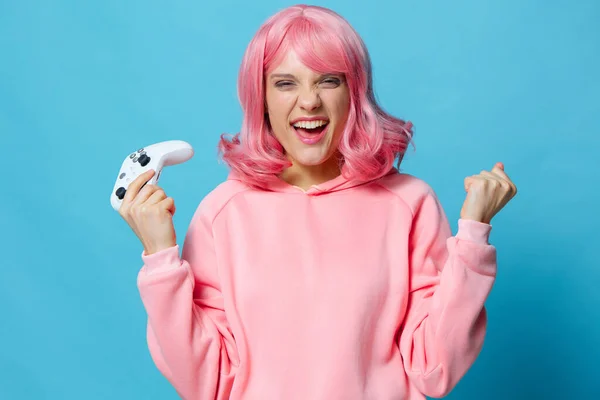 Hermosa mujer con gamepad rosa sudadera entretenimiento fondo azul — Foto de Stock