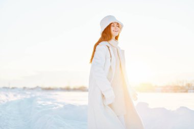 Beyaz önlüklü, kış manzaralı genç bir kadın. Temiz hava alıyor.