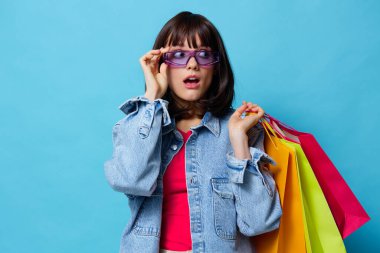 Renkli alışveriş çantaları olan kot ceketli genç bir kadın izole edilmiş.