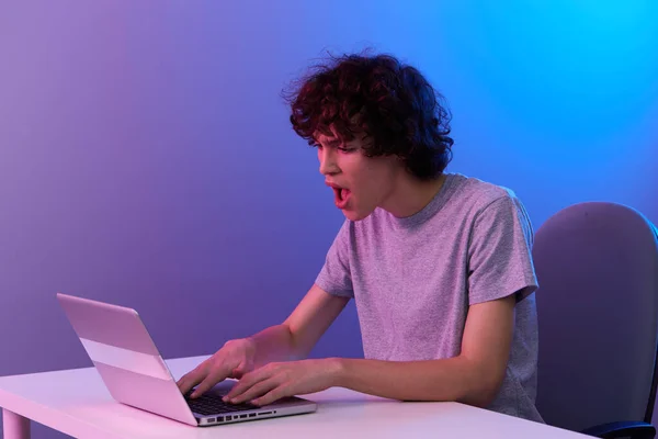 curly guy sitting at the table gaming laptop isolated background