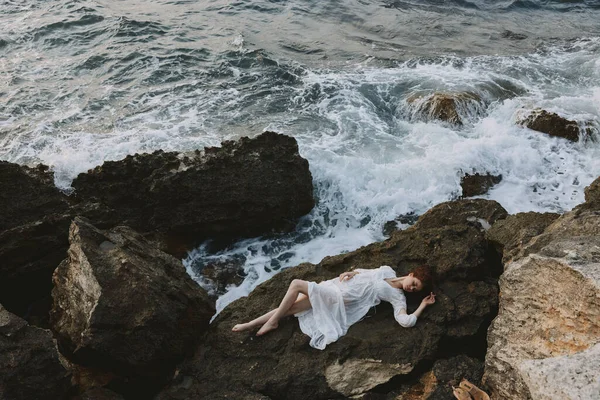 Barefoot woman in a white dress lying on a stone in a white dress unaltered — Stock Photo, Image