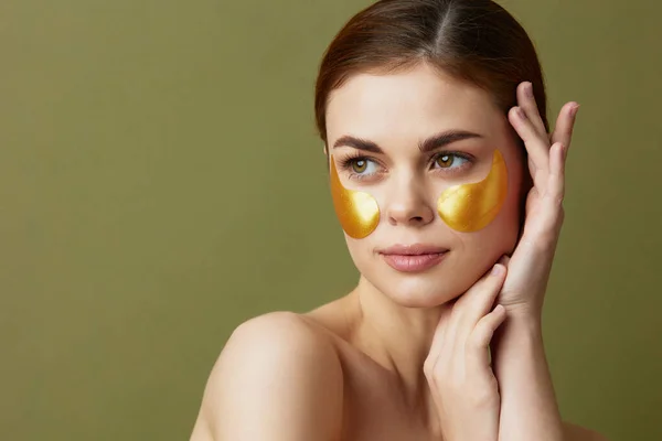 Jonge vrouw gouden vlekken schone huid glimlach poseren groene achtergrond — Stockfoto