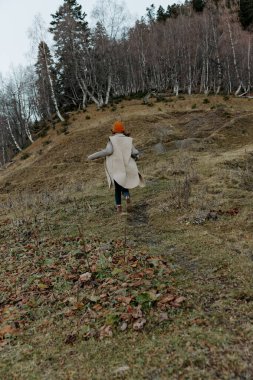 Sonbahar kıyafetleri içindeki genç kadın doğa ağaçları rahatça dolaşır.