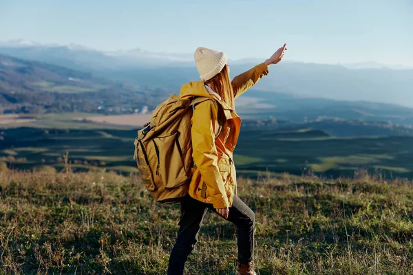 모자 가방을 든 노란 옷을 입고 산을 여행하는 여자 — 스톡 사진