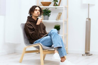 Yakışıklı adam, arka planda not defteri ışığı olan fikirler yazıyor.