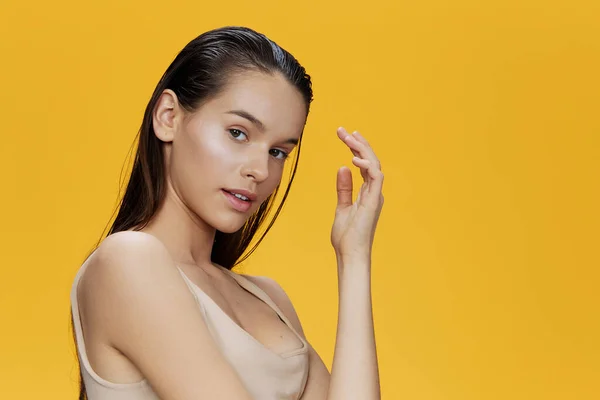 Brunette poseren hand in de buurt gezicht gele achtergrond — Stockfoto