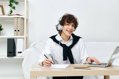 Genç kız, masadaki koltukta dizüstü bilgisayarla iletişim kuruyor.