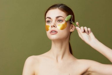 Güzel kadın, yeşim taşlı altın yamalar, temiz cilt gülümsemesi, izole edilmiş arka plan.