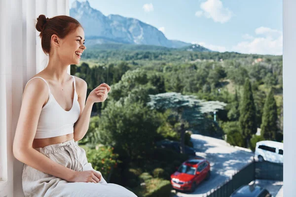 Bella donna ammira la vista delle montagne sul balcone aperto dell'hotel in posa — Foto Stock