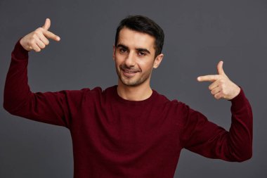 Başarılı adam gülümsüyor. El hareketi. Kırmızı kazak.