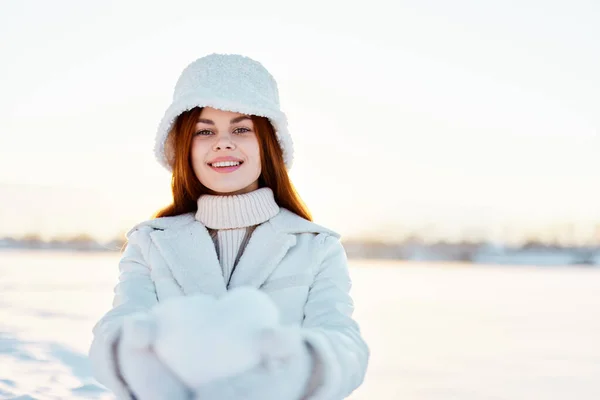Kadın gülümse kış havasında yürü beyaz ceketli, elinde kar var. — Stok fotoğraf