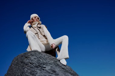 Sonbahar elbiseli turist bir kaya manzarası üzerinde duruyor. Mavi gökyüzü rahatlaması.
