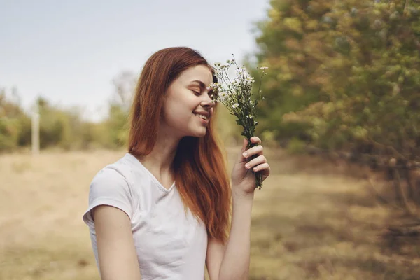 Donna con fiori bianchi in mano sta riposando nel campo e alberi Nello stile di vita di sfondo — Foto Stock
