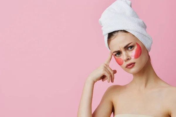 Woman pink patches on the face with a towel on the head pink background — Stock Photo, Image