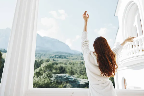 Woman long hair in a white bathrobe staying on the balcony in a hotel Relaxation concept — Fotografia de Stock