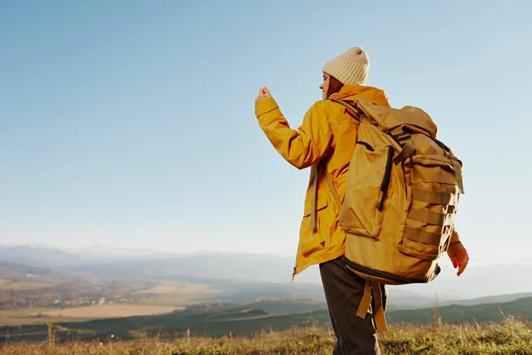 Жінка в жовтій куртці в капелюшному рюкзаку подорожує горами релаксація — стокове фото
