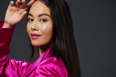 Pembe elbiseli güzel bir kadın. Göz kamaştırıcı. Gri arka plan.