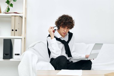 Masadaki koltukta oturan bir adam dizüstü bilgisayarla iletişim kuruyor.