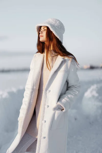 帽子の冬の風景の中に白いコートの若い女性が歩く新鮮な空気 — ストック写真