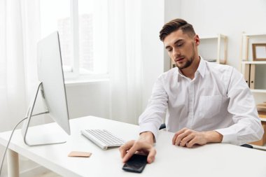Beyaz gömlekli, iş yerinde çalışan yakışıklı bir ofis çalışanı.