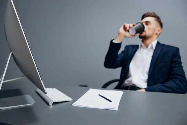 Un homme en costume fatigué verre de café travaille devant un ordinateur fond gris — Photo