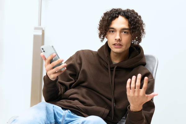 Genç bir adam telefon teknolojisiyle odada sohbet ediyor. — Stok fotoğraf