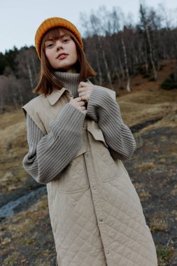 Sonbahar kıyafetleri içindeki genç kadın doğa ağaçları manzarayı gezer.