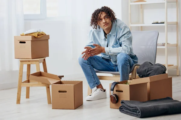 Schöner Kerl sitzt auf einem Stuhl mit Kisten im Inneren — Stockfoto