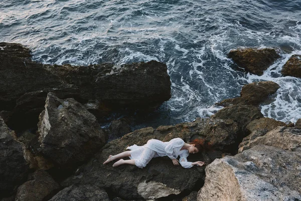 Woman in a white dress lying on a stone in a white dress view from above — Stock Photo, Image