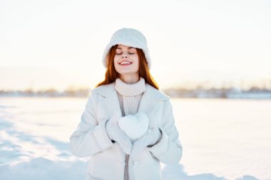 Güzel kadın gülümse kış havasında yürü beyaz palto ellerinde kar geziyor